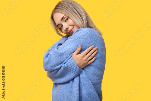 Photography Young woman hugging herself on yellow background