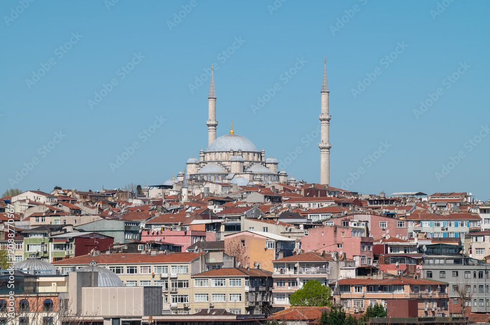 Fototapeta premium horizontal photo of a cityscape view of a ottoman mosque in a hill surrounded by buildings with a clear sky.