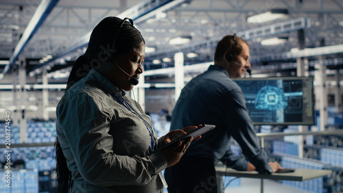 Canvas Print African American system administrator uses AI on a tablet in a server farm to help customers resolve website hosting problems