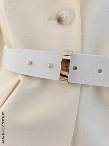 Close view of white coat waist with decorative belt and button details, fashion styling, modern apparel.