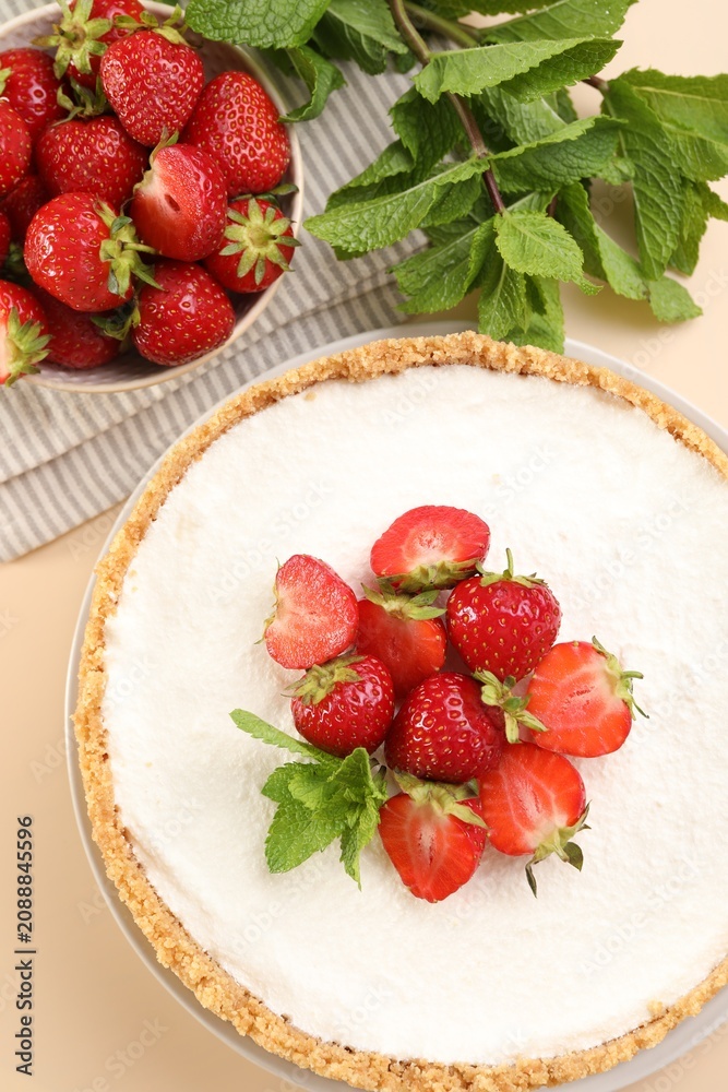 Obraz premium Yummy cheesecake with strawberries and mint on beige table, flat lay