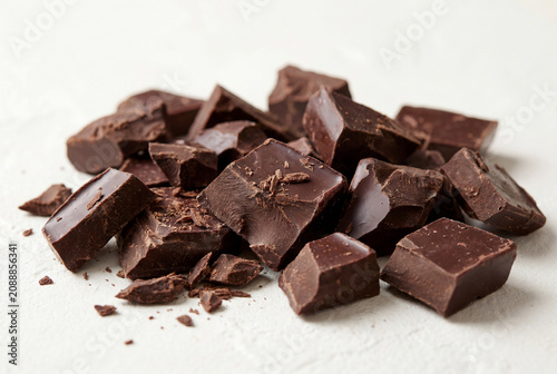 A scattered pile of rich dark chocolate chunks resting on a textured white surface indoors