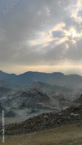 Canvas Print Beautiful landscape of mountain peaks with dramatic crepuscular sun rays breaking through dark clouds