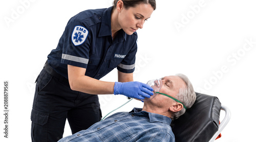 Female Paramedic Administering Oxygen to Senior Male Patient on Stretcher Isolated