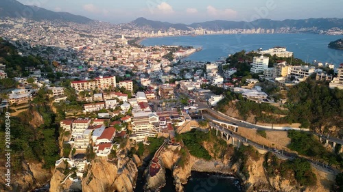 Breathtaking aerial view of Acapulco Bay, Mexico, showcasing the sprawling cityscape, lush hills, and deep blue Pacific Ocean under a bright sky, popular tourist destination