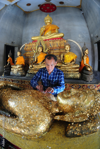 Thai Buddhists are applying gold leaf to