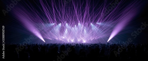 A vast crowd watches a spectacular display of purple and white stage lights
