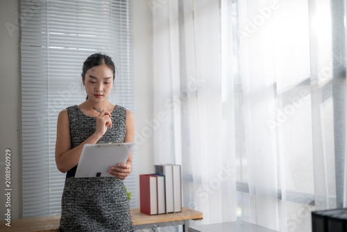Woman Reading Document Near Window in Bright Office Environment