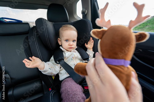 Принти на полотні Mother trying to entertain baby in car seat with a toy