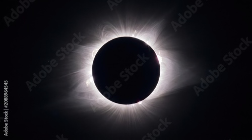 Total solar eclipse with glowing corona against dark sky.