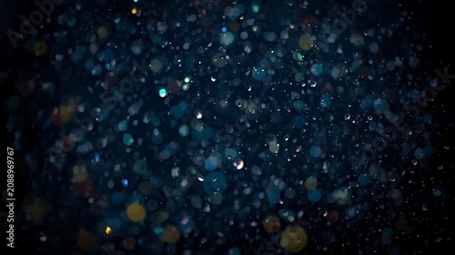 photography of colorful raindrops falling from the sky on a dark night with a candid photography style.