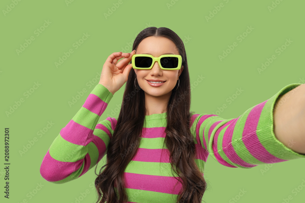Fototapeta premium A woman smiles while taking a selfie with bright sunglasses