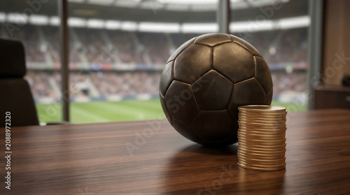 Soccer ball and stack of gold coins on office desk