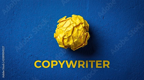 Bright yellow crumpled paper ball and copywriter text on textured blue background representing writing process with letters against textured word copywriter bold communication storytelling