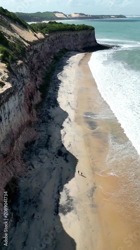 Cinematic aerial drone footage capturing the stunning  and dramatic cliffs of Praia do Madeiro and Praia do Golfinho in Pipa, famous for wild dolphins, Brazil – 2025