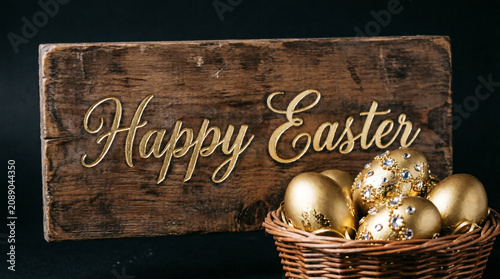 Rustic Happy Easter sign with pastel decorated eggs in wicker basket celebrating spring joy.