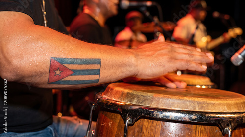 Musician with Cuba flag tattoo playing conga drum live