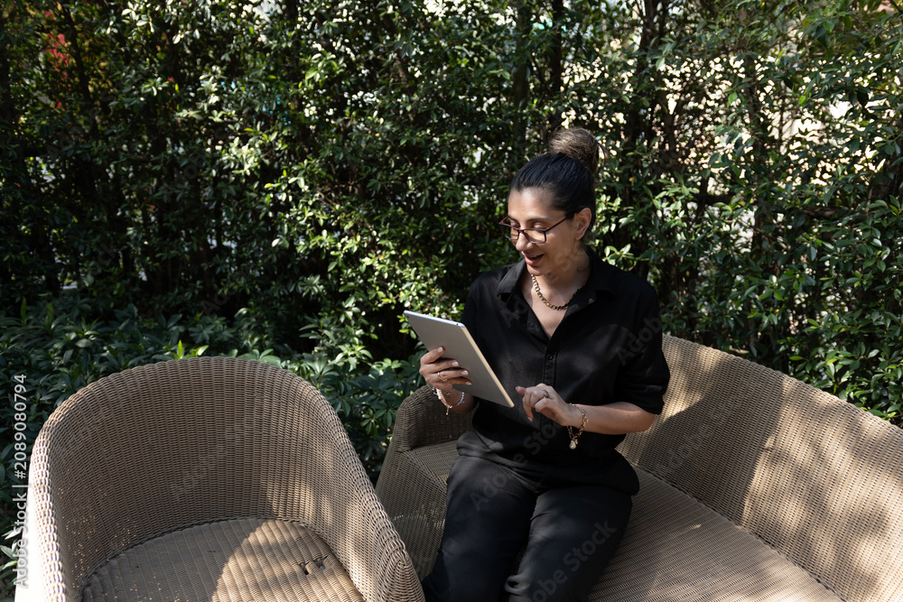 Obraz premium Horizontal view of a female freelancer staying connected online with her digital tablet while relaxing in nature.