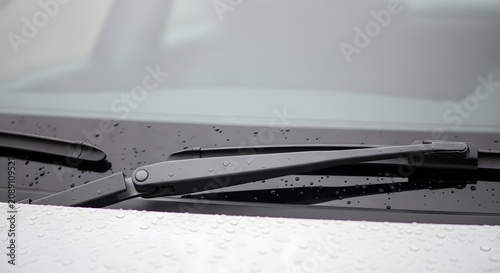 Close-up of a car windshield wiper with water droplets, illustrating rainy weather and vehicle maintenance.