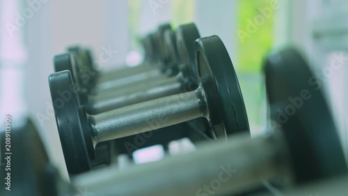 woman hand picking dumbbell from rack in gym.