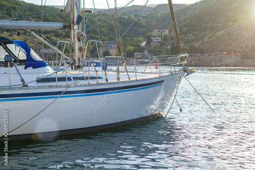White Sailboat Moored in a Calm Bay by Green Hills