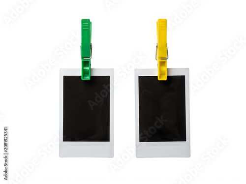 Two blank polaroid photos hanging from colorful plastic clothespins on white background transparent background