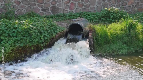 Waste water sewage from a pipe into the river. Water pollution, environment contamination concept