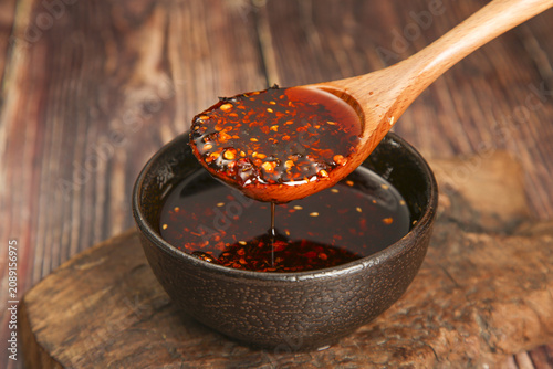 Fotografie Szechuan Chili Oil with Red Peppers - Spicy Asian Seasoning in Wooden Spoon and