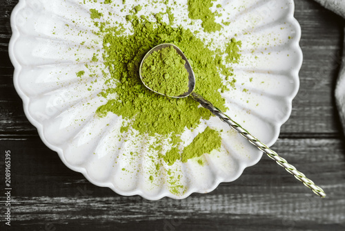 Foto Spirulina powder on a white plate with a metal spoon