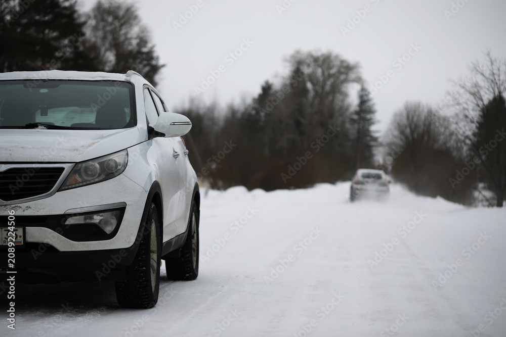 Naklejka premium Winter Road with Snow-Covered SUVs in Forested Countryside