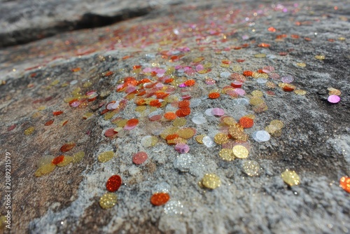 Close-up of Colorful Confetti Scattered Across a Textured Stone Surface, Evoking a Festive Celebration