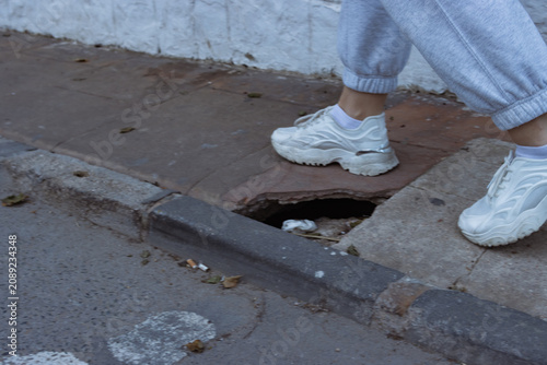 Картината върху платно Person's feet wearing white sneakers on a city sidewalk