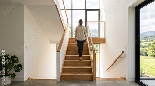 Woman walking upstairs in a bright modern home with scenic landscape view