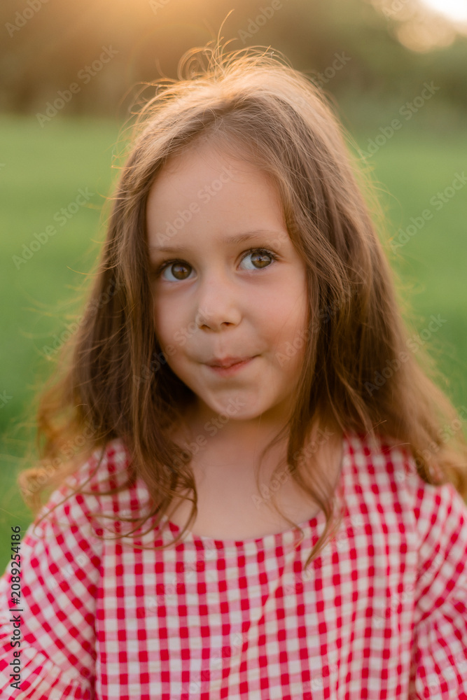 Fototapeta premium little girl runs in a field on the grass at sunset in summer