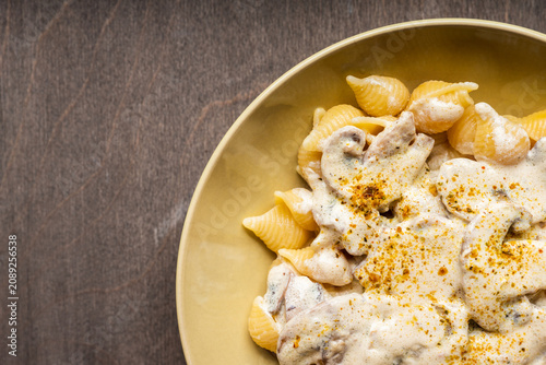 Homemade pasta with creamy mushroom sauce on dark wooden background. Shot from above.