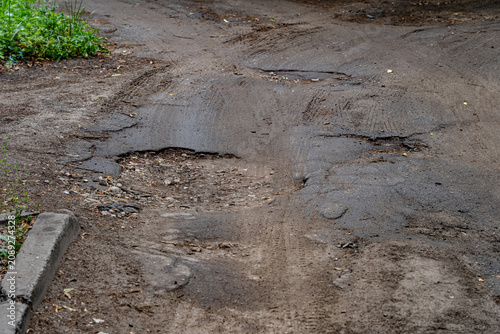 the yard and the road are in poor condition with remnants of asphalt, repairs and construction