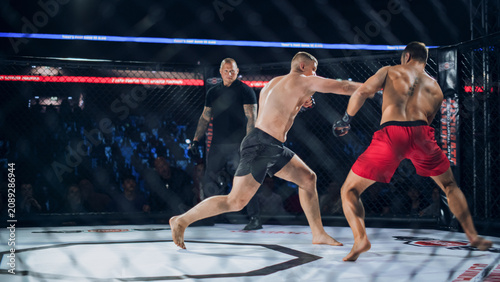 MMA Fighters Fight Trade Heavy Punches in a Live Cage Fight as the Referee Tracks the Action. Fast Striking and Real Contact Drive a Competitive Contest, With Loud Crowd Energy and Fight