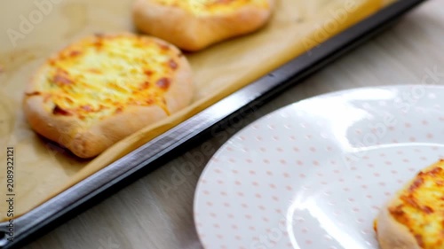 Serving golden cheese topped mini flatbreads from tray to plate with spatula in close view, showing melted topping, crisp edges, warm color, and fresh homemade food presentation