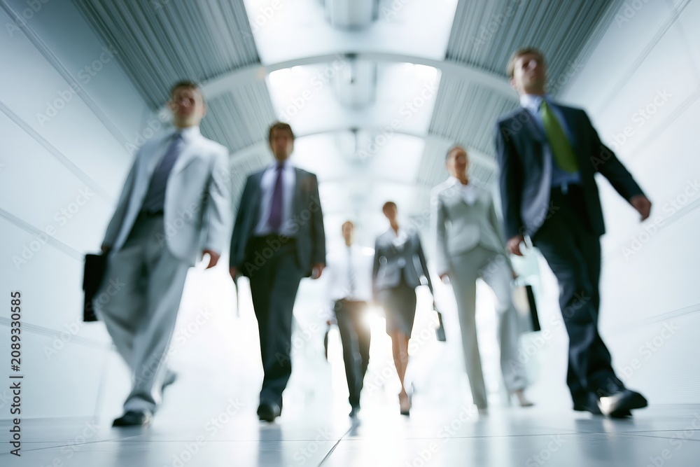 Fototapeta premium Business team walking in modern office corridor, employees moving forward with determination and purposeful steps