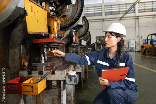 Female factory worker inspecting machinery in industrial plant