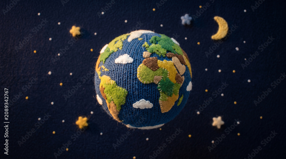 Fototapeta premium Crocheted Earth globe model surrounded by felt stars and moon on a dark blue textured background