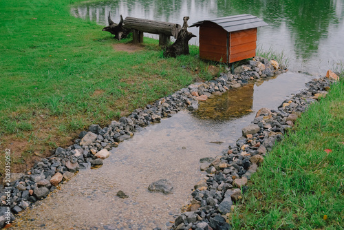 A gentle stream winding through natural rocks and lush green grass, creating a peaceful and refreshing landscape.