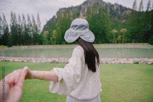 Woman in a cute outfit leading man to the mountain in Thailand. Traveling together. Follow me.