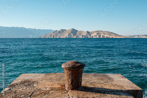 Foto Rusty bollard on a stone pier overlooking the Adriatic Sea in Croatia