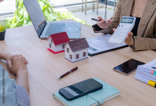 Фотография Real estate agent and a female client holding house models while discussing and comparing property options at the office desk