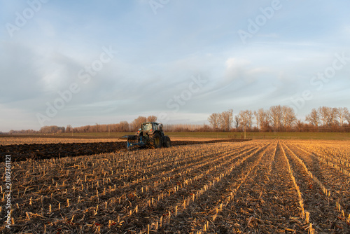 Red tractor plowing agricultural field after harvest, soil cultivation and farm work