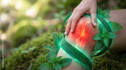 Close up of a knee with glowing red inflammation surrounded by green leaves and natural moss