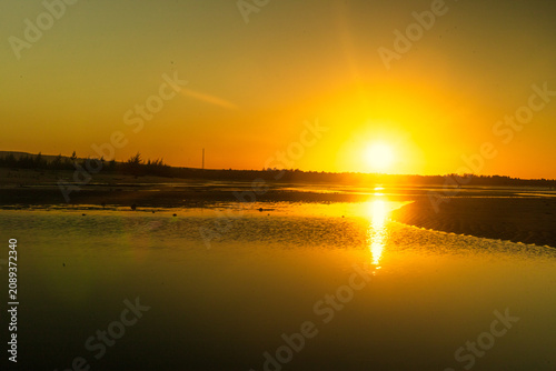 The afternoon grows later at Pasir Putih Beach, when suddenly the sky radiates a golden-yellow hue, reflected in the remaining seawater as the tide recedes near the savanna of Sumba.