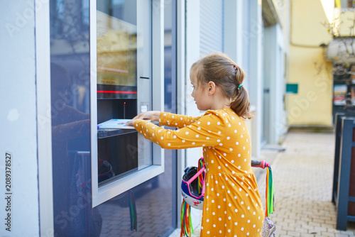 Fotografie Young girl returning books through an outdoor library self-service machine