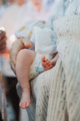 Legs, feet, baby close-up, during the baptism ceremony.